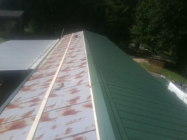 Old rusted panels beside newly installed green metal roofing — Wind Damage Roof Repair by Roofing Brothers in Paris